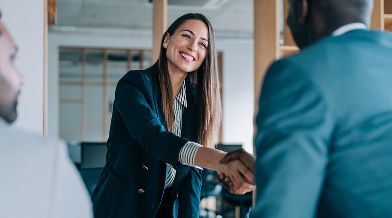 Business woman shaking hands in a board room